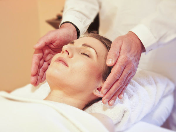 Masaje facial japonés: las manos de la terapeuta trabajan las sienes y el rostro de una mujer tumbada con los ojos cerrados